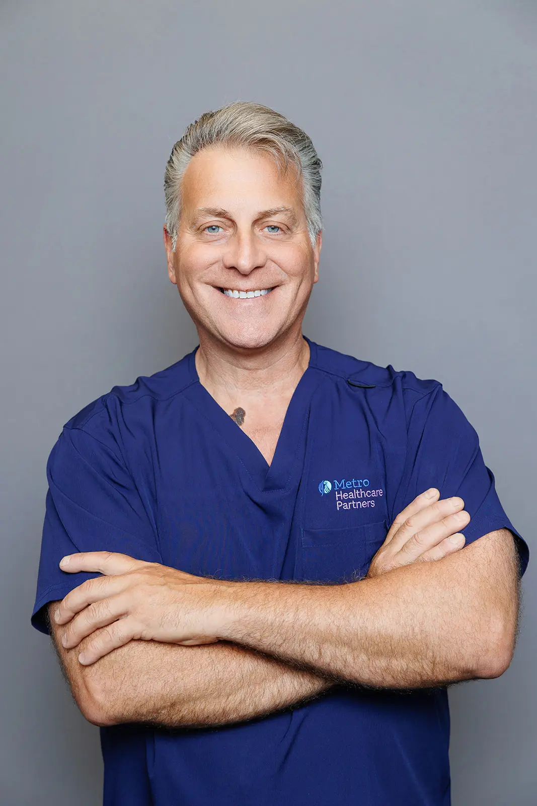 Professional doctor headshot of a male physician in blue medical scrubs in New York City.